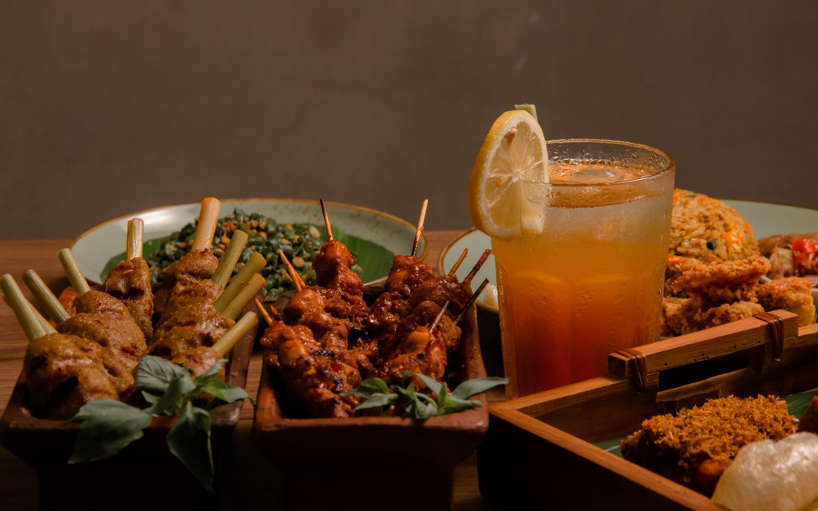 Hidangan sate, nasi, dan teh disusun di meja katering untuk makan bersama